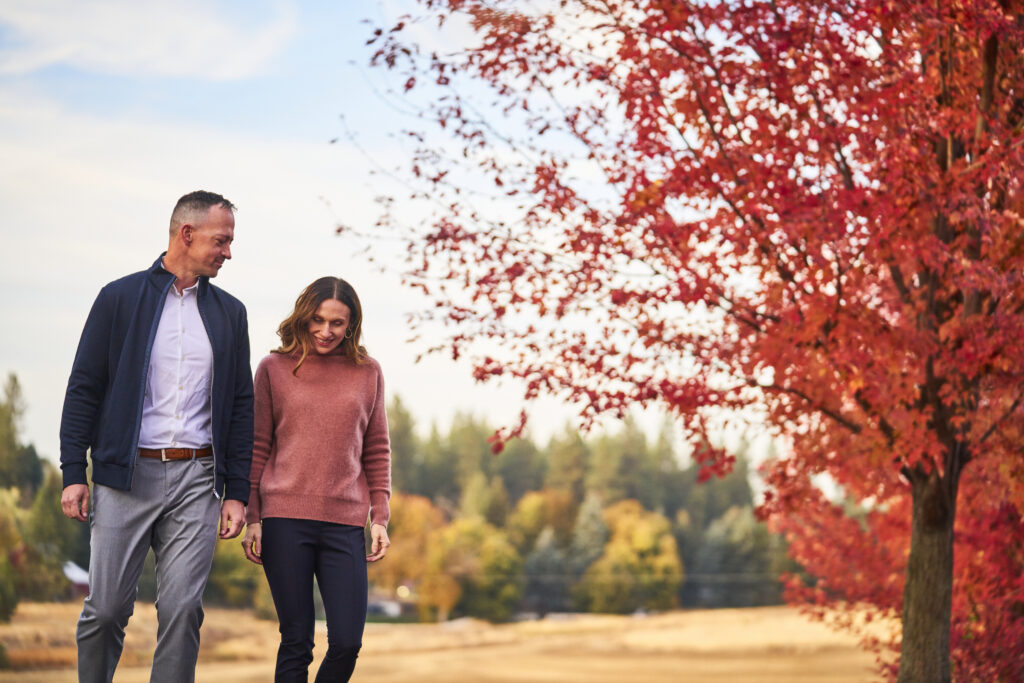 Dr. Travis and Dr. Kat walking through autumn foliage